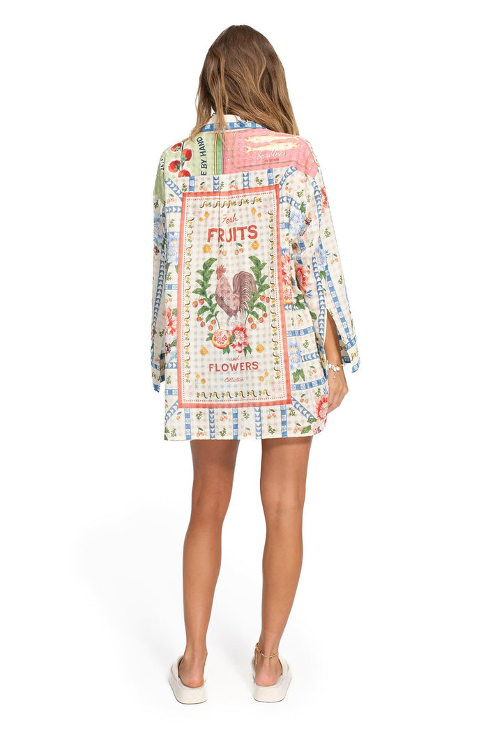 White oversized shirt with vintage-inspired placement print featuring colorful fruit and pattern detail illustrations with decorative text panels on…