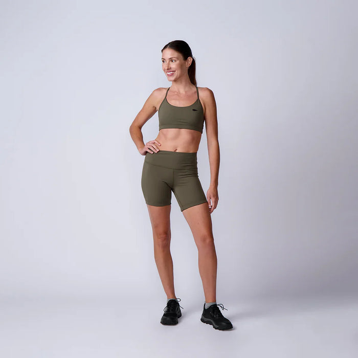 Woman in olive green GORUCK sports bra and shorts, standing in studio, fitness apparel