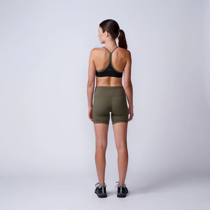 Woman wearing GORUCK olive green athletic shorts and black sports bra, facing away