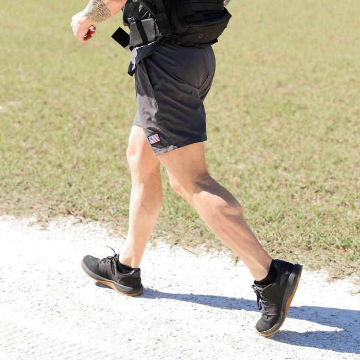 Man rucking outdoors in GORUCK gear, wearing black athletic shoes and cargo shorts