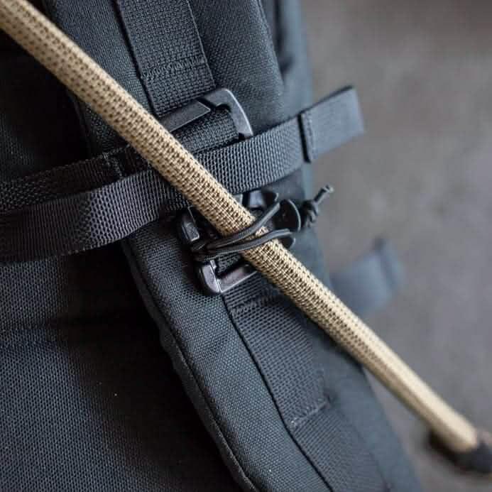 Close-up of GORUCK rucksack with tan utility cord secured by a black buckle and strap