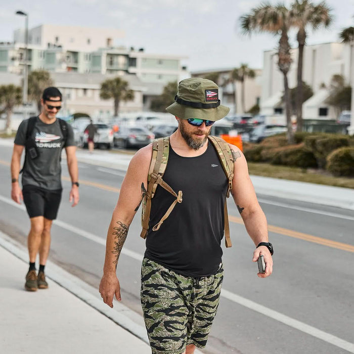 Man wearing GORUCK Ranger Green Boonie Hat and rucking gear walking outdoors on city street