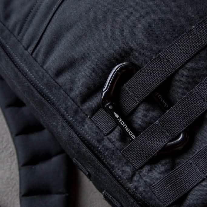 Close-up of GORUCK black rucksack with MOLLE webbing and GORUCK branded carabiner