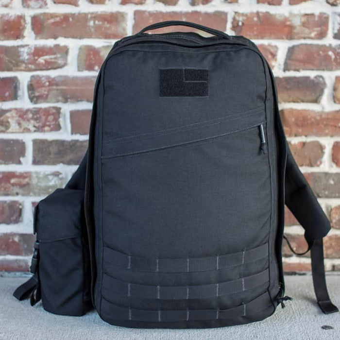 GORUCK black rucksack with full-panel water bottle pocket, shown against a brick wall