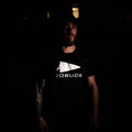 Man wearing black GORUCK reflective tee in low light, showing rucking gear logo.