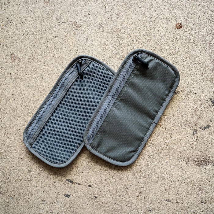 The IFAK (Black + Red Thread + Grey Interior + Red Patch) ROBIC w/ Aquaguard lies open on a textured beige surface, showing its gray interior.