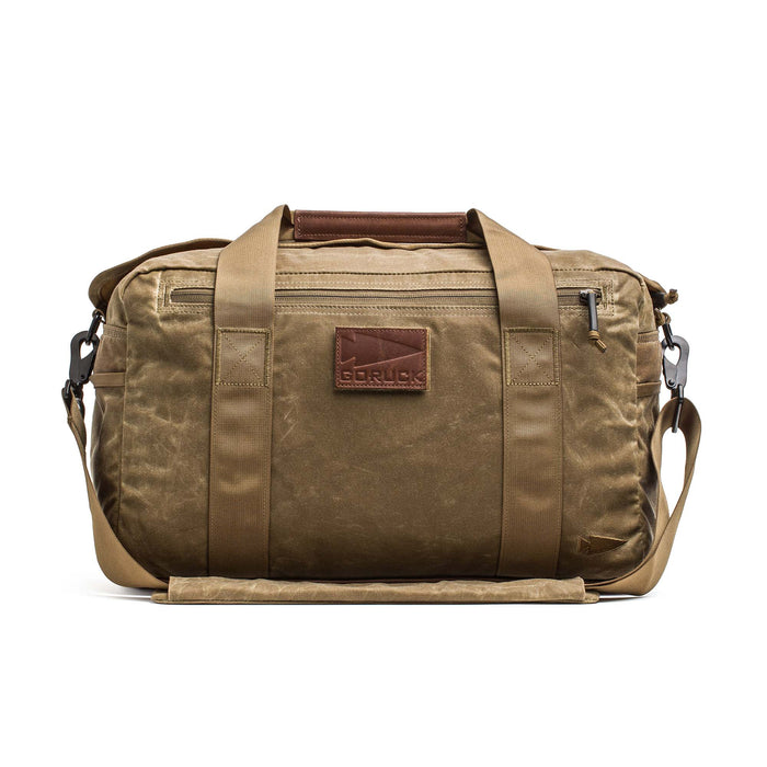 The Kit Bag - Waxed Canvas is a tan duffel inspired by classic aviator kit bags, featuring handles, a shoulder strap, and a leather front patch that reads "GORUCK.