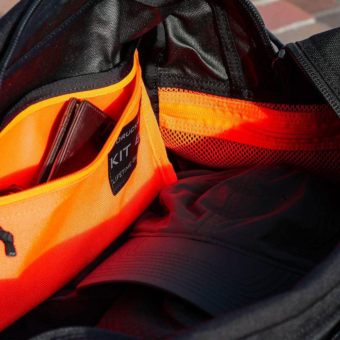 Inside view of GORUCK backpack with orange kit bag, hat, and organized pocket compartments.