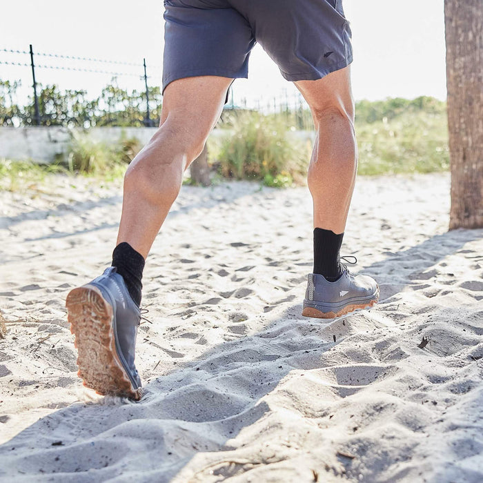Man running on sand in GORUCK rucking shoes and shorts outdoors