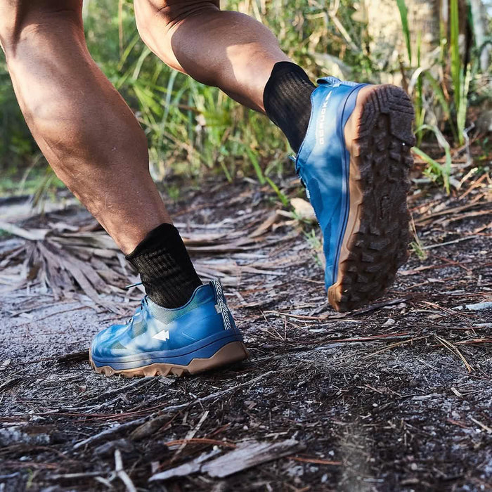 Person trail running outdoors wearing blue GORUCK rucking shoes on rugged terrain