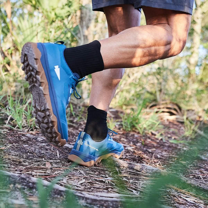 Person hiking outdoors wearing blue GORUCK rucking shoes on a forest trail