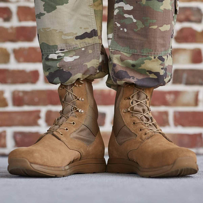 GORUCK brown tactical boots with laces, worn with multicam uniform, brick wall background