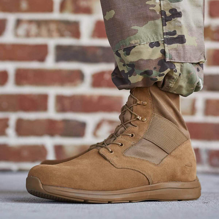 GORUCK brown rucking boot with rugged sole, worn with camo pants, against brick wall