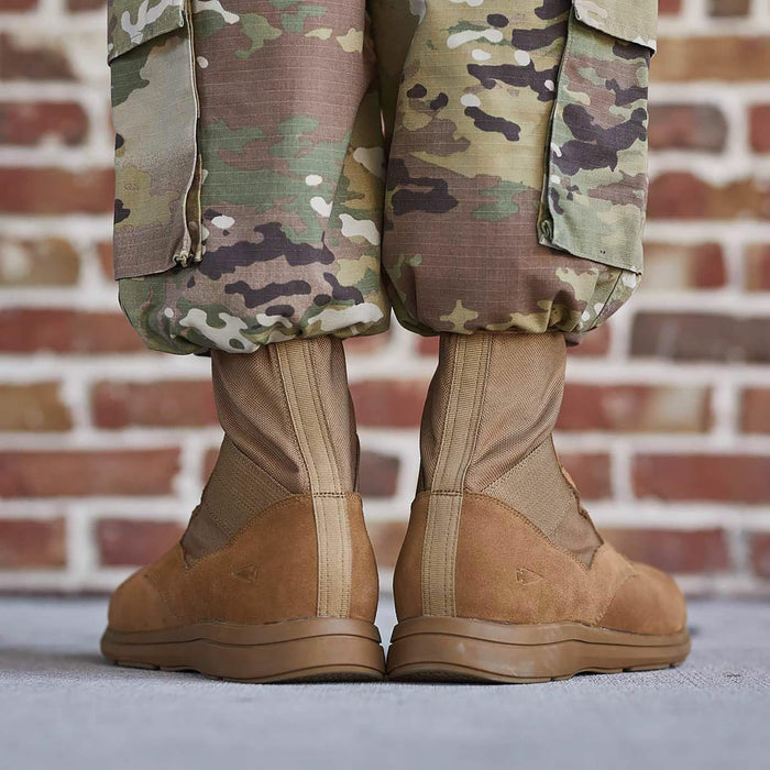 GORUCK brown rucking boots with camo pants, brick wall background, rugged outdoor gear