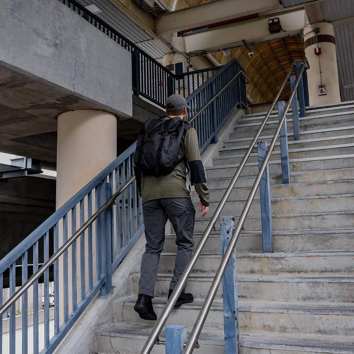 Man with GORUCK black rucksack climbing outdoor concrete stairs, urban setting