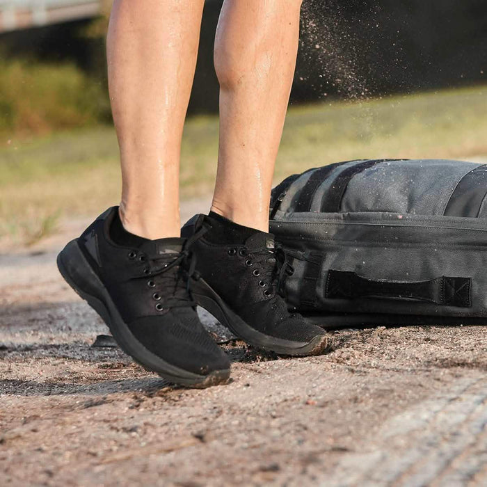 GORUCK Ballistic Blackout Spearhead shoes on person outdoors next to ruck bag on trail