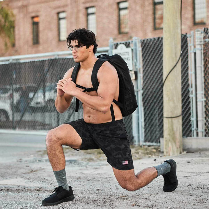Man doing weighted lunge with GORUCK rucksack outdoors in athletic gear