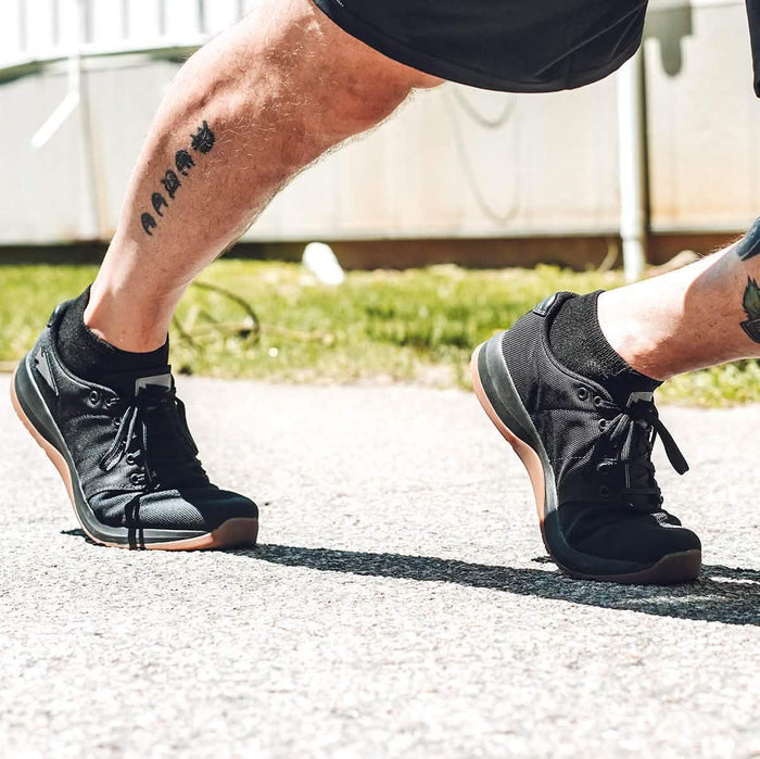 Man running outdoors in GORUCK black rucking shoes, athletic gear focus, sunny day