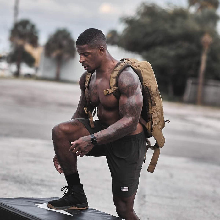 Athletic man rucking outdoors wearing a GORUCK backpack and shorts, training on pavement.