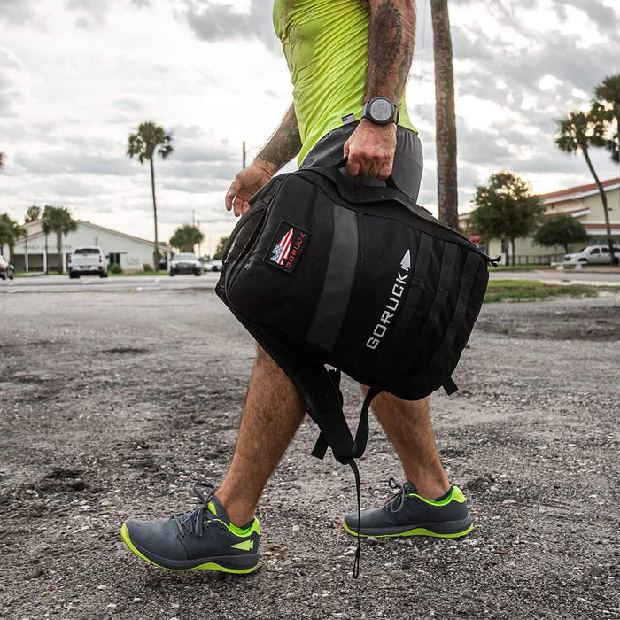 Man rucking outdoors with GORUCK backpack, athletic gear, and running shoes