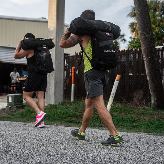 Men rucking outdoors with GORUCK backpacks and sandbags, athletic training gear visible