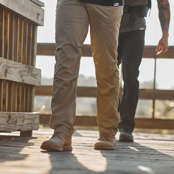 Two people rucking outdoors in GORUCK pants and rugged footwear on a wooden trail.