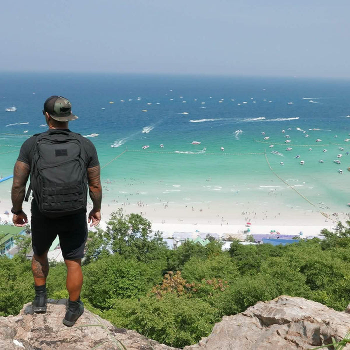 Man wearing GORUCK black Challenge Shorts and backpack overlooking a scenic beach