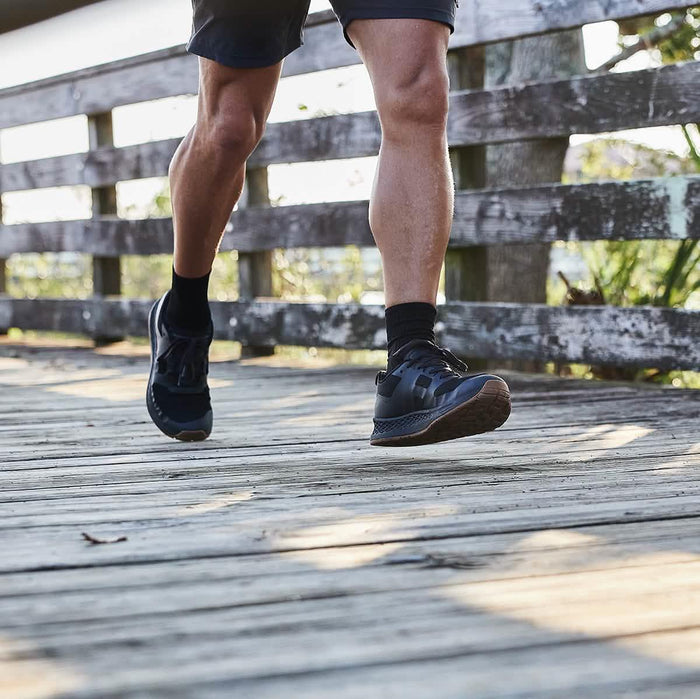 Man wearing GORUCK black rucking shoes running on a wooden outdoor trail