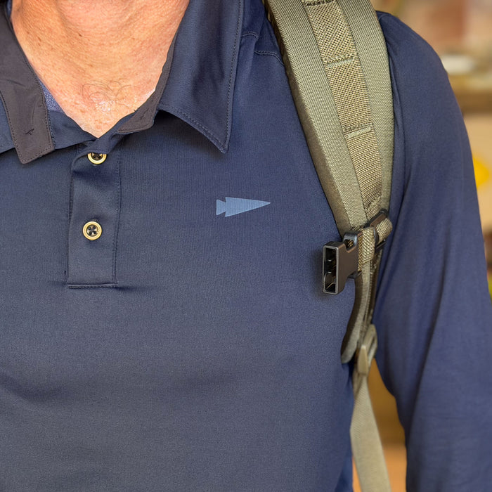 A person is wearing the Men's Long Sleeve Rucking Polo in blue, made in the USA, with a backpack strap over their shoulder.