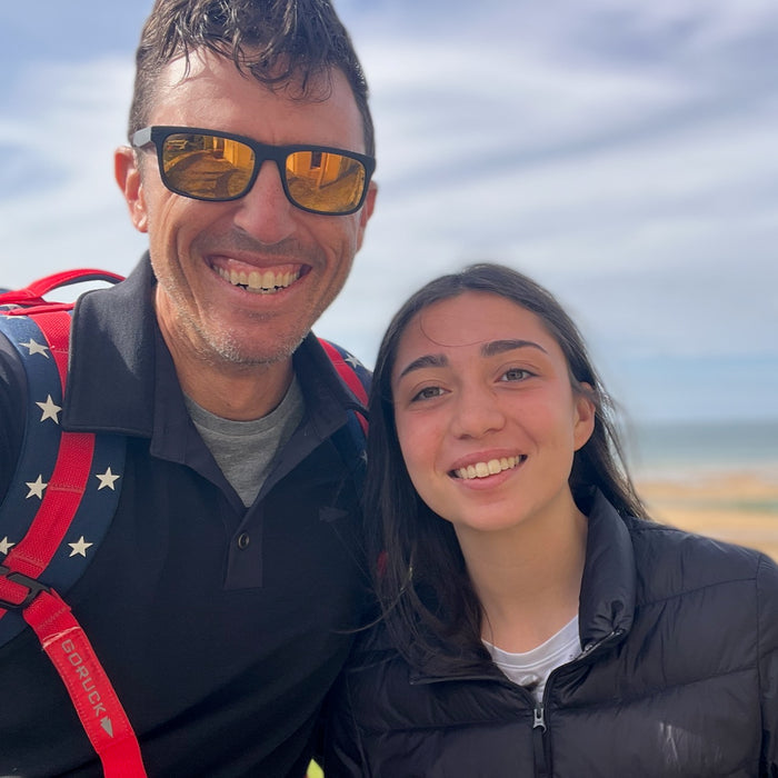 A man and girl smile outdoors against a landscape and sky, both in jackets; the man wears the Men's Rucking Shirt - Merino Wool.
