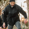 Man rucking outdoors in GORUCK gear with backpack and black jacket on a trail.