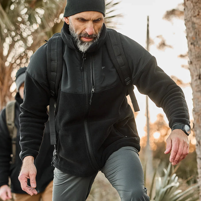 Man rucking outdoors in GORUCK gear with backpack and black jacket on a trail.