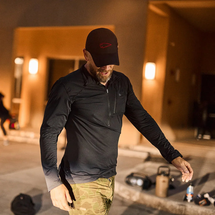 Man in GORUCK black performance half zip long sleeve shirt and camo pants outdoors at night