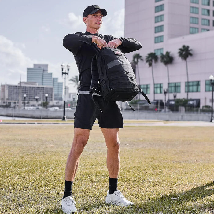 Man in GORUCK performance tee and shorts with backpack outdoors in urban park