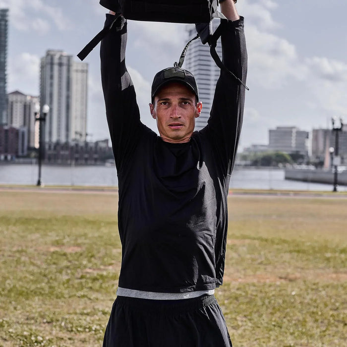 Man wearing GORUCK black longsleeve performance tee lifting rucksack outdoors