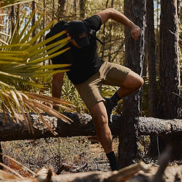 Man in GORUCK gear rucking through forest, climbing over fallen tree in outdoor setting