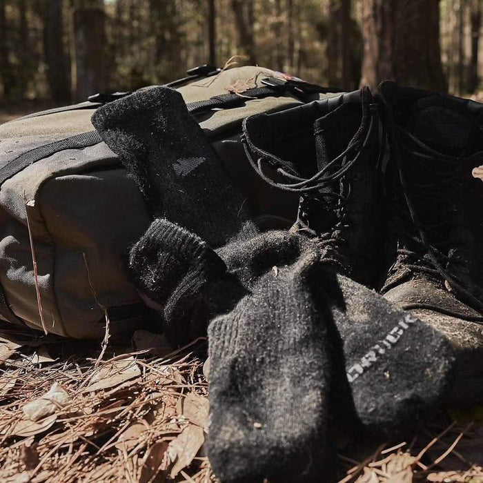 GORUCK rucking gear with black merino socks and boots on forest ground