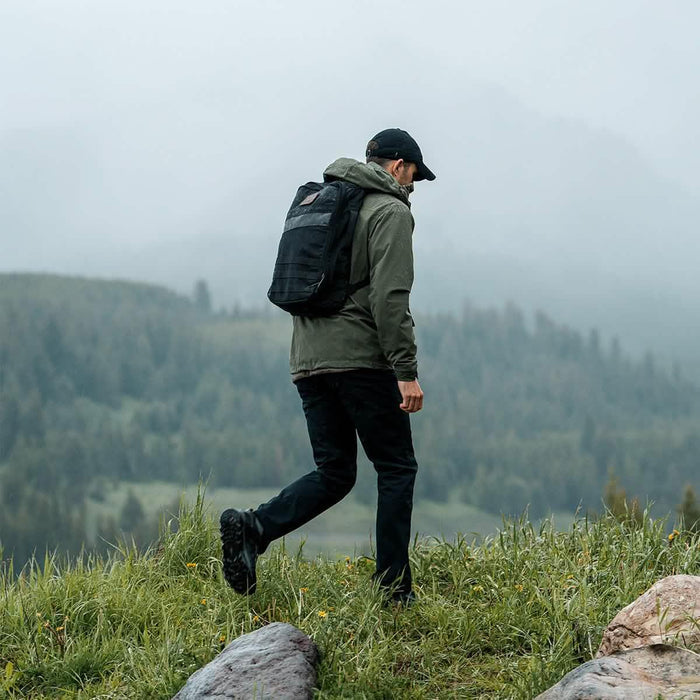 Man rucking outdoors in misty mountains, wearing GORUCK backpack and outdoor gear