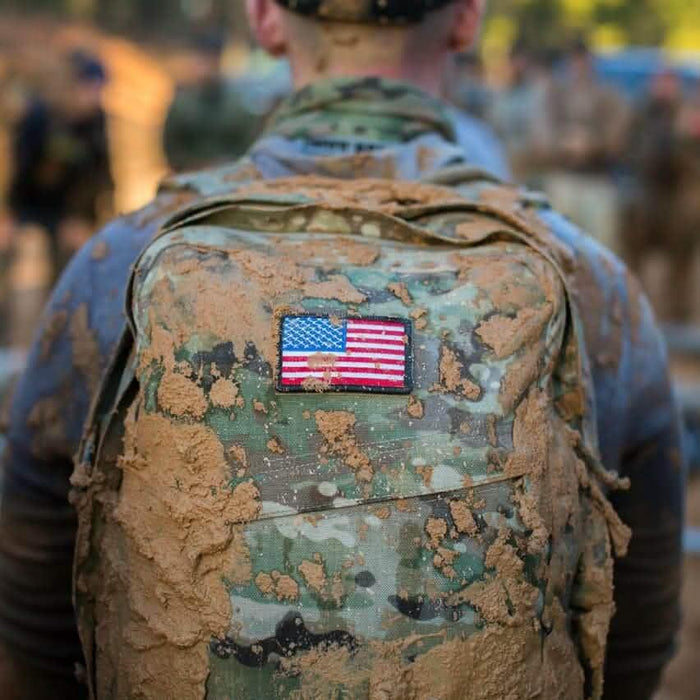 GORUCK camouflage rucksack with American flag patch, muddy from outdoor rucking event