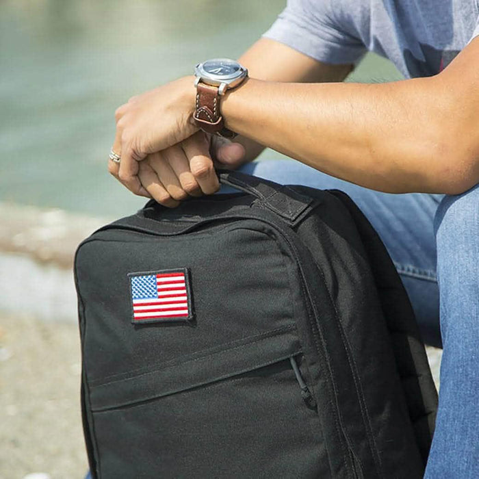 Man outdoors with GORUCK black rucksack featuring American flag patch