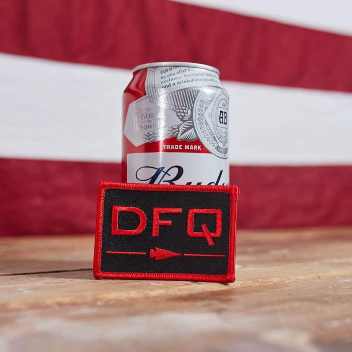 GORUCK DFQ black and red patch on wood table with beer can and American flag background