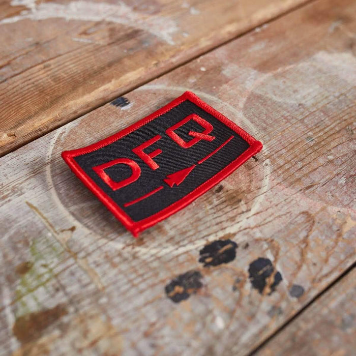 GORUCK DFQ black and red embroidered patch on rustic wooden surface