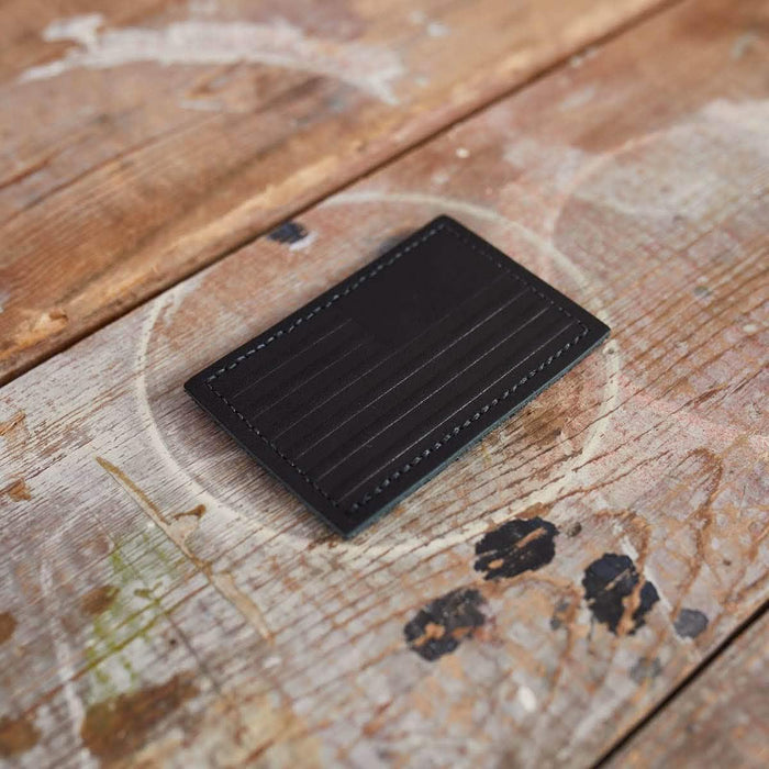 GORUCK black leather card holder with reverse flag detail on rustic wooden surface