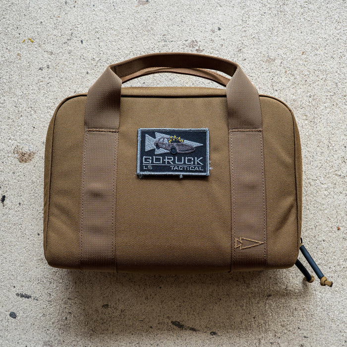 The brown Pistol Rug with handles and a "GORUCK Tactical" patch sits on a light textured surface—ideal as a modular pistol case or magazine pouch.