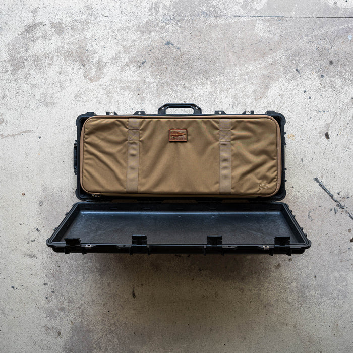 An open Rifle Case, hard and black, displays a tan fabric bag inside, resting on a concrete floor.