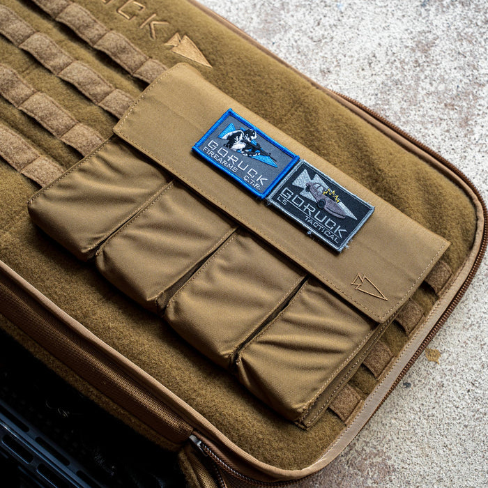 A brown Rifle Case with patches reading "GORUCK firearms gear" displayed on a textured surface.