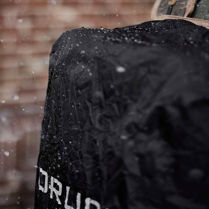 GORUCK waterproof black rucksack cover in rain against brick wall