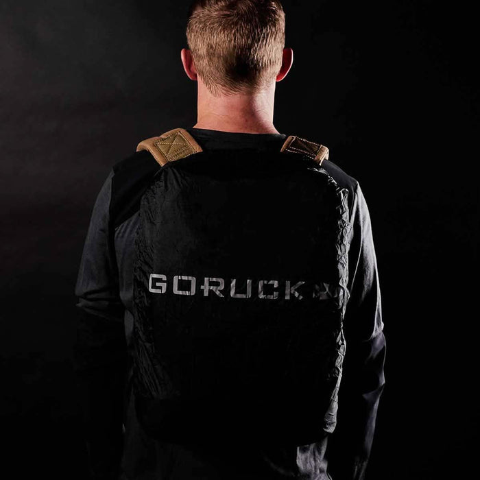 Man wearing black GORUCK backpack with tan straps, rucking gear branding visible