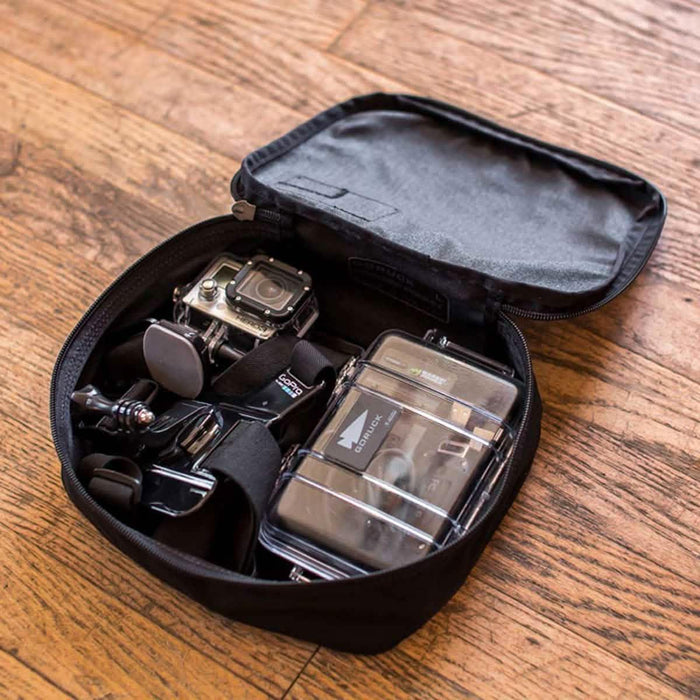 GORUCK Shadow Pocket bag on wood floor holding GoPro camera and accessories
