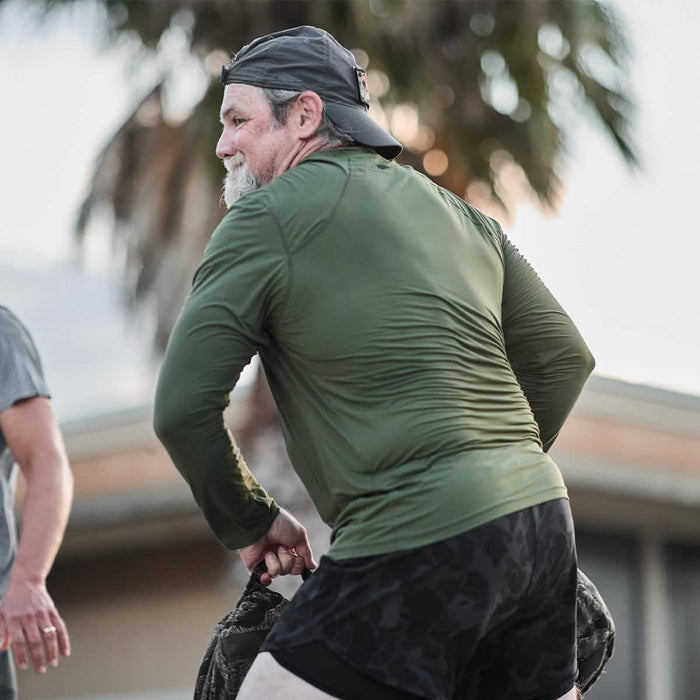 Man wearing GORUCK ToughMesh long sleeve shirt lifting weighted ruck outdoors